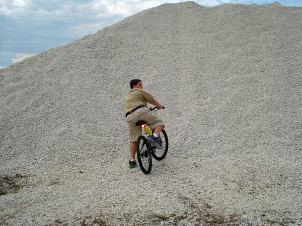Alex Jones trying to ride his bike up a sand hill