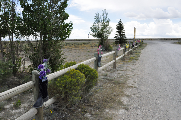 a fence is lined with boots filled with flowers