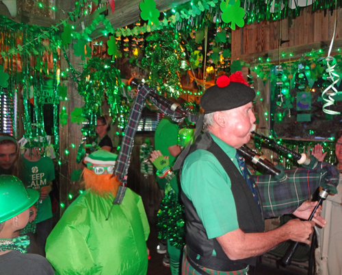 Bagpipe player and a green dude in the parade
