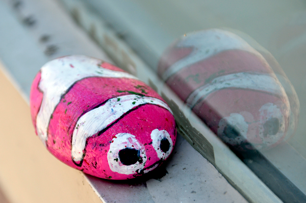 pink and white painted rock with eyeballs