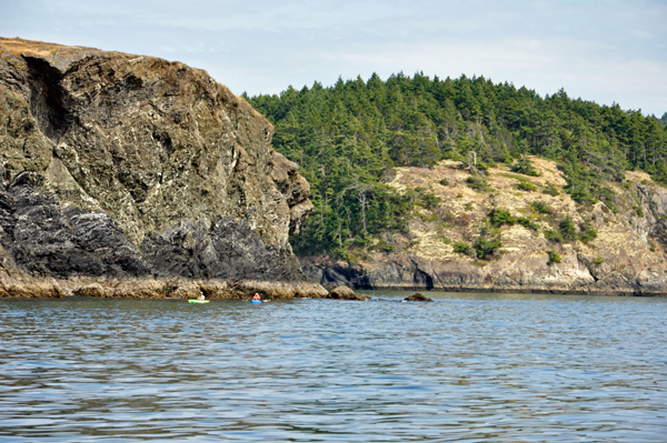 Kayakers and a face in the cliff.