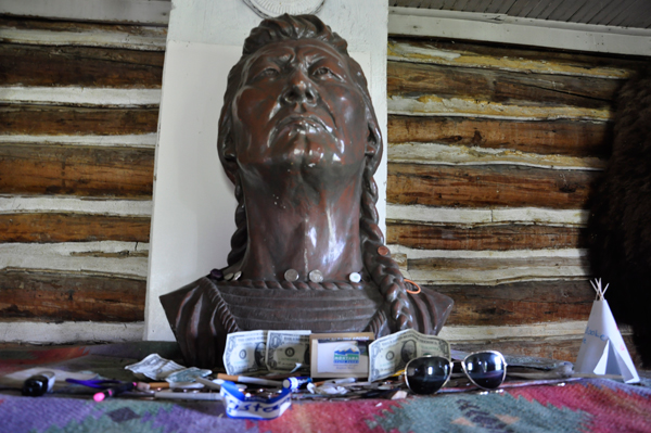 money, trinkets and stuff by a bust of the Chief