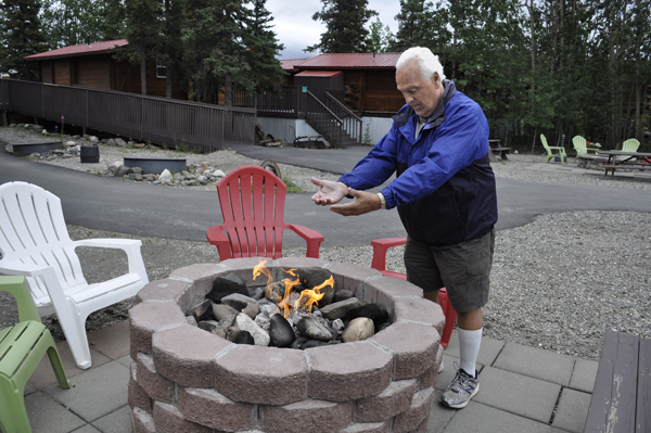 Lee Duquette warms his hands by the fireplace