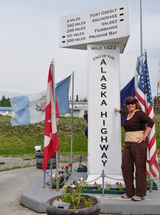 Karen Duquette and the large white milepost for Mile 1422 of the Alaska Highway