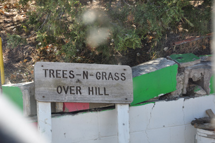 sign - trees N grass over hill
