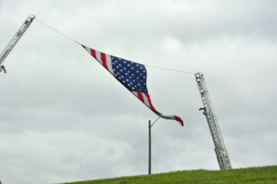 USA flag held up by 2 firetrucks