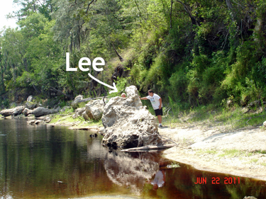 Lee peeking out from behind a big rock