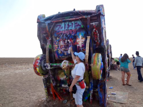 Karen Duquette spray painting a caddy at Cadillac Ranch