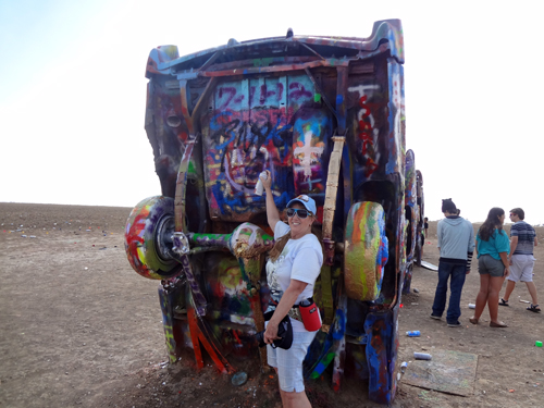 Karen Duquette spray painting a caddy at Cadillac Ranch