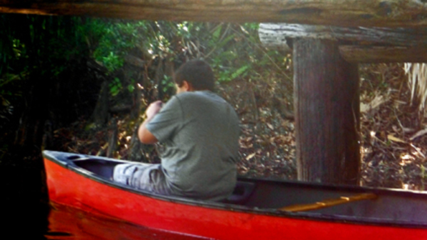 The grandson of the two RV Gypsies canoeing under a log bridge