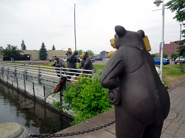 a big bear taking pictures of three bears fishing.