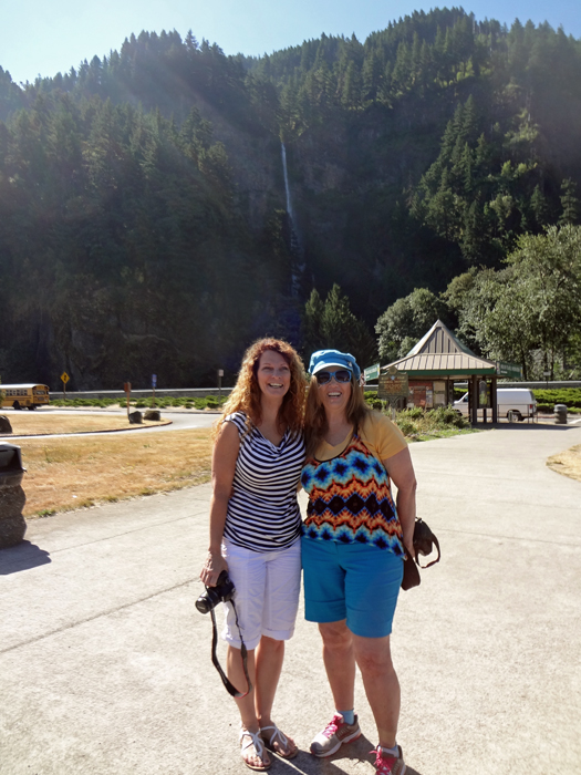 Karen Duquette and her sister in the parking lot with Multnomah Falls in the background.