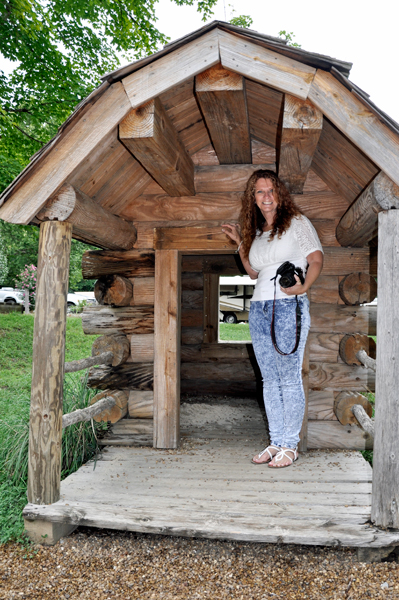 Ilse in the doorway of a miniature log cabin
