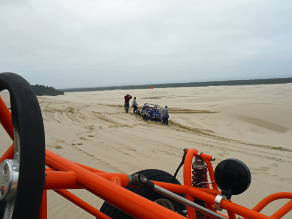 The blue dune buggy is stuck in the sand