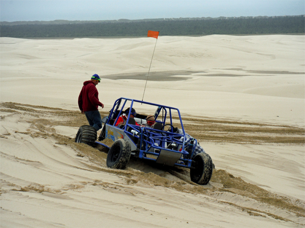 The blue dune buggy is stuck in the sand