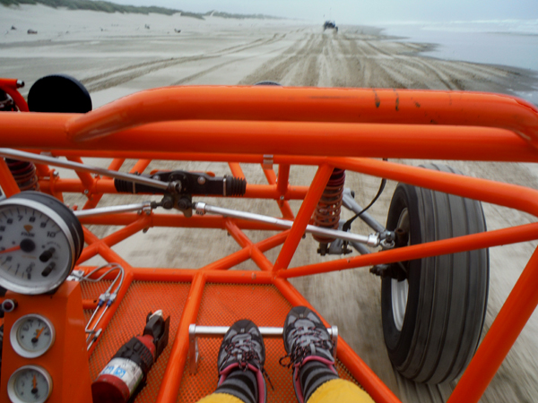 The dune buggies speed along the beach.