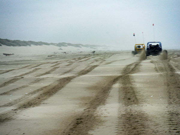 The dune buggies speed along the beach.