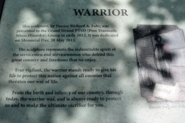sign about the Warrior metal sculpture