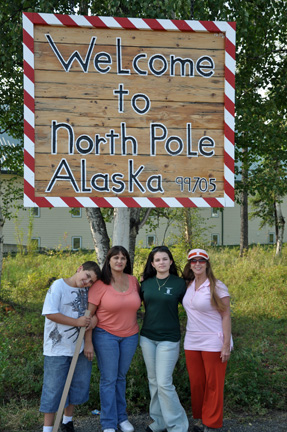 family with sign - welcome to North Pole Alaska