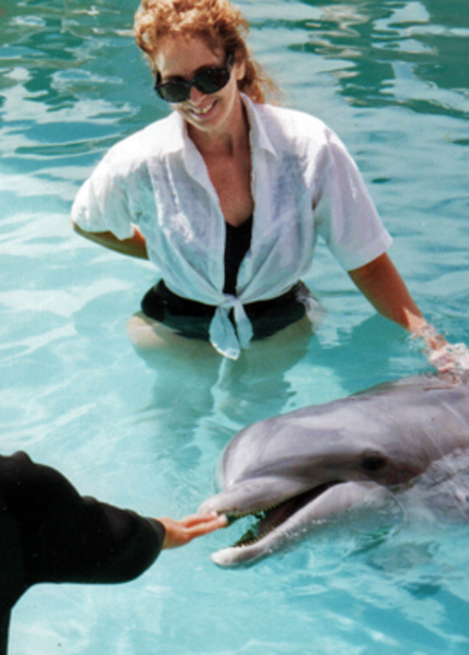 Karen Duquette touching a dolphin
