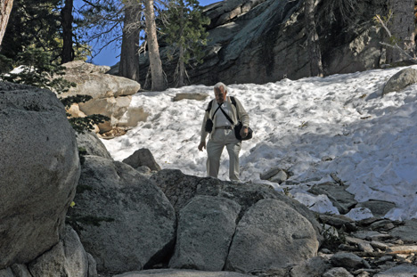 Lee climbs a small rocky hill that has patches of icy snow